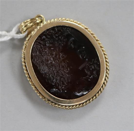 A yellow metal and carved intaglio oval pendant, carved with a bust to sinister, 31mm